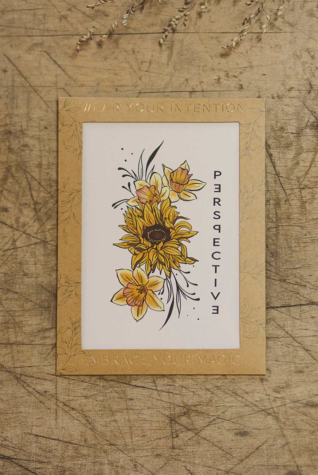 "Perspective" Sunflower and Narcissus temporary tattoo sheet from Orchid and Pine Tiny Intentions collection displayed on table.