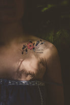 Person wearing a "Tout Est Possible" botanical tattoo on their shoulder as a daily affirmation with sun and shadows.