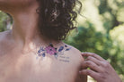 Person wearing a "Tout Est Possible" botanical tattoo on their shoulder as a daily affirmation.
