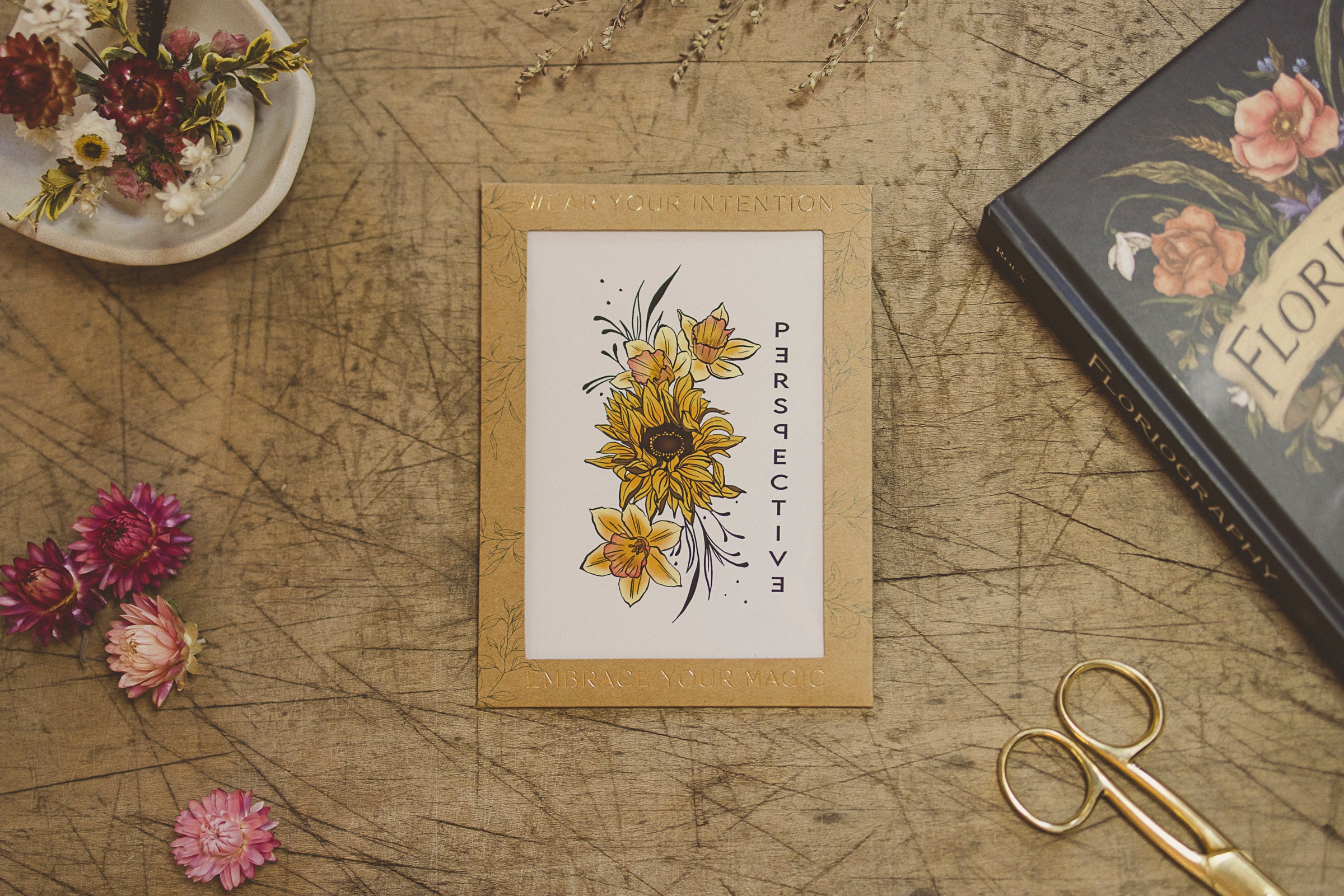 "Perspective" Sunflower and Narcissus temporary tattoo sheet from Orchid and Pine Tiny Intentions collection displayed on table.